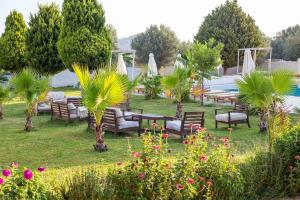 a garden with couches and tables and palm trees at Evita in Faliraki