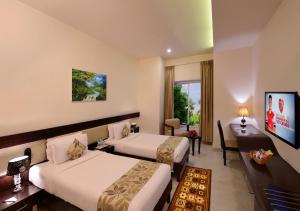 a hotel room with two beds and a desk at Royal Ritis in Shimoga