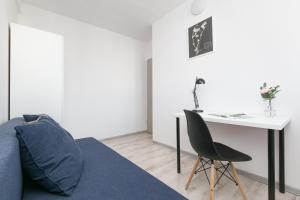 a living room with a blue couch and a desk at Rooms4Less in Gdańsk