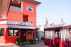 un bâtiment rouge avec une tente en face dans l'établissement Motel Karibe, à Fratta Polesine