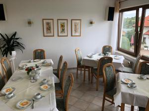 ein Esszimmer mit weißen Tischen und Stühlen sowie einem Fenster in der Unterkunft Hotel Erfurtblick in Erfurt