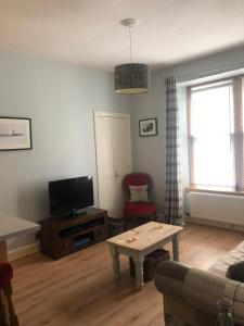 a living room with a couch and a tv and a table at The Abbeyhill Bonnie Thistle in Edinburgh