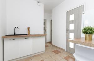 a kitchen with white cabinets and a sink at Rooms4Less in Gdańsk