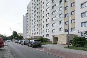 a street with cars parked in front of a tall building at Rooms4Less in Gdańsk