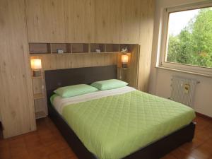 a bedroom with a bed with green sheets and a window at Appartamento Panoramico Lungopassirio in Merano