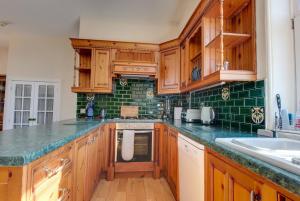 a kitchen with wooden cabinets and green tiles at Carnegie Library: Shakespeare Apartment 3 Bedroom in Mexborough