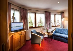 um quarto de hotel com uma televisão, uma cadeira e um sofá em Vital - und Wellnesshotel Hanneshof em Filzmoos
