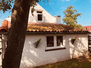 una casa de ladrillo blanco con dos ventanas y un árbol en Farmhouse near beach, en Kloosterzande