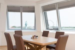 ein Esszimmer mit einem Tisch, Stühlen und Fenstern in der Unterkunft Yourapartment Prater in Wien