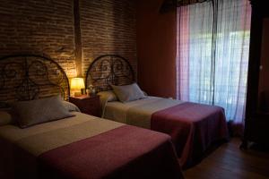 a bedroom with two beds and a brick wall at Casa Rural Caenia Grupos in Traguntia