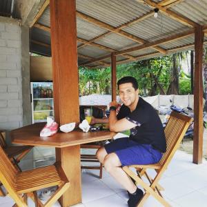 a man sitting in a chair at a table at Bungalow in Karimunjawa
