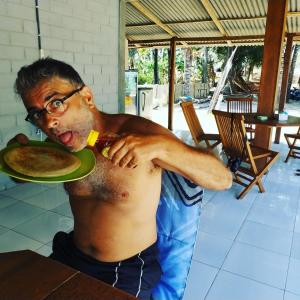 a man eating a plate of food with his mouth at Bungalow in Karimunjawa