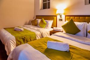 a hotel room with two beds with green and white sheets at Wintry Hills By Lemas in Nuwara Eliya