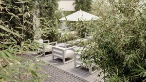 フランクフルト・アム・マインにあるThe Pure, Frankfurt, a Member of Design Hotelsの白い椅子と傘と木々のあるパティオ