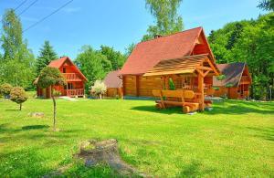 una cabaña de madera en un campo de césped verde en Bieszczady Resort, en Polańczyk