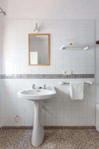 Baño blanco con lavabo y espejo en Hostal Las Nieves, en Ibiza