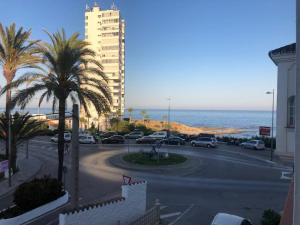 ein Parkplatz mit Palmen und einem Gebäude und dem Meer in der Unterkunft Apartamento 8 mamia costa in Torreguadiaro