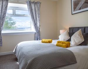 ein Schlafzimmer mit einem Bett mit gelben Kissen und einem Fenster in der Unterkunft Carvetii - Borthwick House - Ground floor flat in Kinghorn