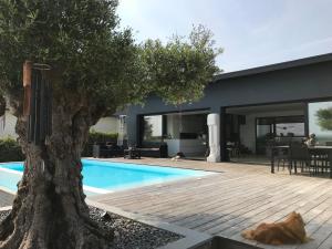 a house with a tree next to a swimming pool at Villa de luxe avec piscine, vue imprenable in Séné