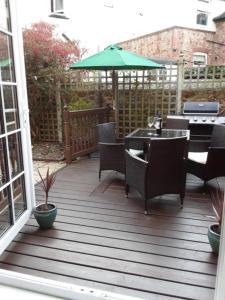 a patio with tables and chairs and an umbrella at Dumble Cottage in Minehead