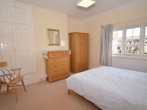 a bedroom with a bed and a dresser and a window at Dumble Cottage in Minehead