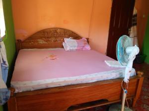 - une chambre avec un lit en bois et un ventilateur dans l'établissement Wasini Raha Snorkeling and Diving, à Wasini