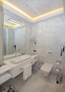 a bathroom with a toilet, sink and mirror at Wyndham Grand Istanbul Levent in Istanbul