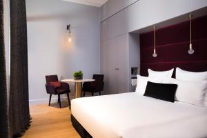 a bedroom with a large white bed and a table at Hôtel Cardinal Bordeaux Centre in Bordeaux