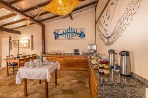 a room with a table and a kitchen with a counter at Pousada Costa do Sapê in Angra dos Reis