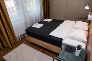 a bedroom with a bed with white pillows and a chair at Apartman Donner Centar IV in Subotica
