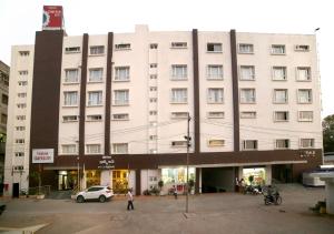卡努尔Triguna Clarks Inn Kurnool的一座白色的大建筑,前面设有停车场