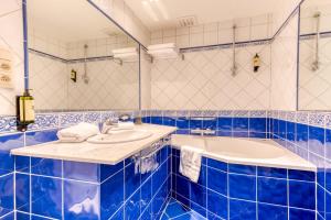 Hôtel Imperi'Ale في Comblain-la-Tour: حمام باللون الأزرق والأبيض مع حوض استحمام ومغسلة