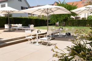 un patio con tavoli, sedie e ombrelloni di H+ Hotel Zürich a Zurigo