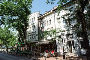 un edificio en una calle de la ciudad con gente sentada afuera en Apartman Donner Centar IV, en Subotica