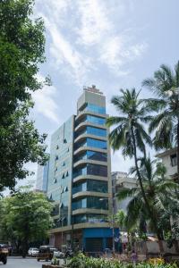 a tall building with palm trees in front of it at Hotel Grace Galaxy in Mumbai