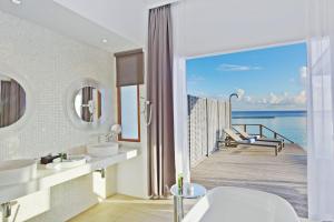 a bathroom with two sinks and a view of the ocean at Kuramathi Maldives in Rasdhoo