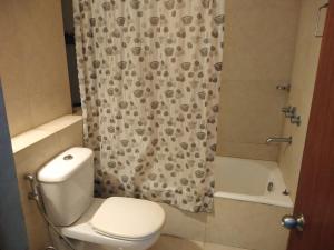 a bathroom with a toilet and a shower curtain at Gardenia 29 in Raichak +43 photos