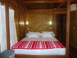 uma cama vermelha e branca num quarto de madeira em Simeulue Surflodges em Lasikin