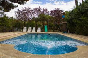 una piscina con sillas en un patio en El Chalet del Pinar, en Cuenca