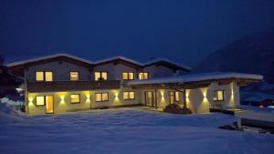 una casa con luces en la nieve por la noche en Apart Andreas, en Ried im Zillertal
