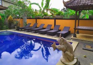 a statue of a monkey next to a swimming pool at Swan Inn in Ubud