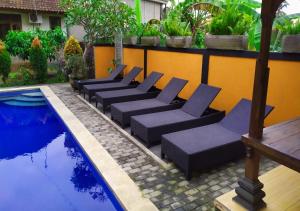 a row of lounge chairs next to a pool at Swan Inn in Ubud