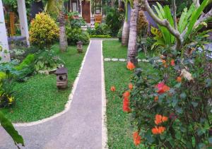 a walkway in a garden with flowers and palm trees at Swan Inn in Ubud