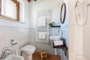 a white bathroom with a toilet and a sink at Casetta Tartuchino in Semproniano
