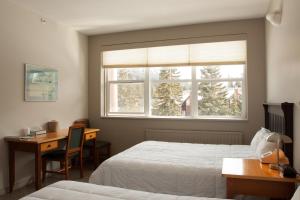 1 dormitorio con 2 camas, escritorio y ventana en YWCA Banff Hotel, en Banff