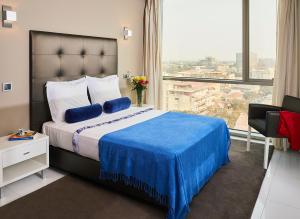 um quarto de hotel com uma cama e uma grande janela em RK Suite Hotel em Luanda