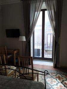 um quarto com uma grande janela e uma mesa e cadeiras em B&B A Casa Di GioSi em Catânia