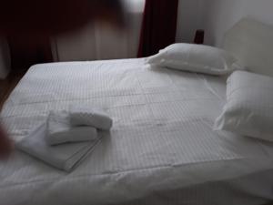 een wit bed met witte lakens en handdoeken erop bij Apartament Coresi in Braşov
