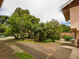 una entrada en un patio con árboles y una casa en Pousada Recanto São Benedito en Campos do Jordão