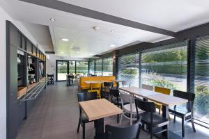 a restaurant with tables and chairs and large windows at B&B HOTEL Pau Zénith in Pau